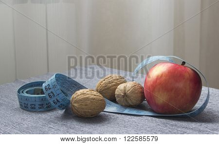 diet (healthy food) with fresh red apple nuts and measure tape for loss weight