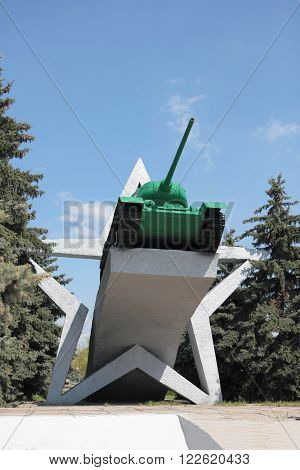 Bronevaya past war machine stands on a concrete pedestal surrounded by young trees.
