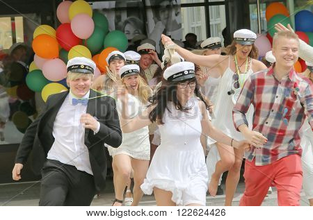STOCKHOLM SWEDEN - JUN 10 2015: Group of happy teenagers wearing graduation caps running out from school after graduation from high school at the school Globala gymnasiet June 10 2015 Stockholm Sweden