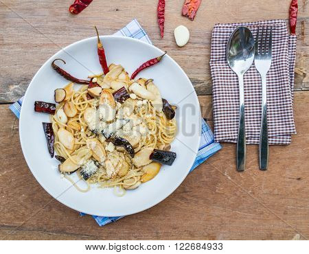 Spaghetti stir dried chili add eringi mushroom on white dish on wooden table. top view.