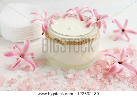 Fresh skin care cream, flowers, pink bath salt, cotton pads. Natural beauty treatment.
