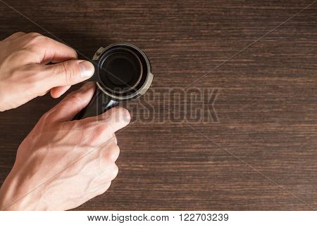 Man preparing ground coffee in brew unit for brewing on kitchen counter. Top view image