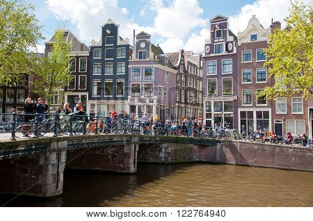 AMSTERDAM-APRIL 27: King's Day boating through Amsterdam canals people have fun on the bridge on April 27 2015. King's Day (Koningsdag) is held on 27 April (the king's birthday) every year.