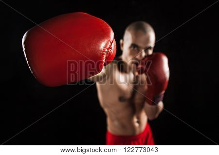 The young male athlete kickboxing on a black background with kapa in mouth. concept fury in the fight
** Note: Shallow depth of field