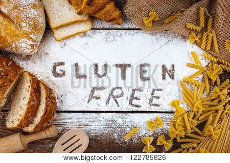 Top view studio shot of gluten-free word with flour and bread on wooden table