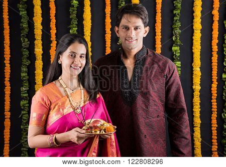 Portrait of Maharashtrian couple holding a puja thali, indian couple holding puja thali or pooja thali, indian couple celebrating diwali, laxmi pujan, asian couple and puja thali, couple doing prayer