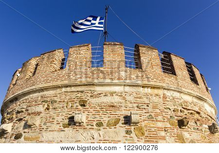 White Tower and Greek flag in Thessaloniki in Geece.