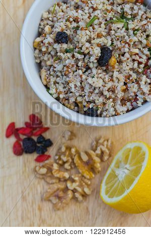 A bowl of delicious fresh quinoa and bulgar weat with parsley walnuts goji berries and blue berries sprinkled with olive oil and lemon juice