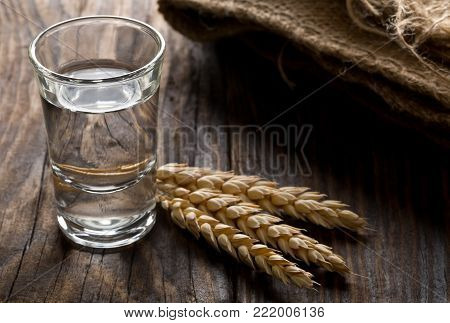 German hard liquor Korn Schnapps in shot glass with wheat ears on rustic wooden table