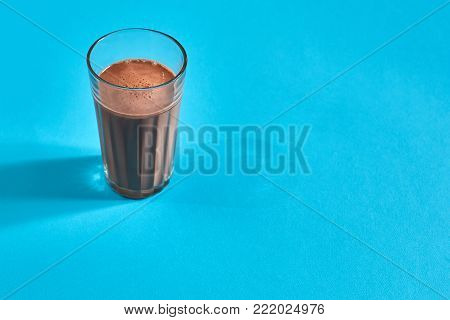 Chocolate milk on blue background with space for text or design. Top view. Still life. Flat lay. Copy space. Dessert.
