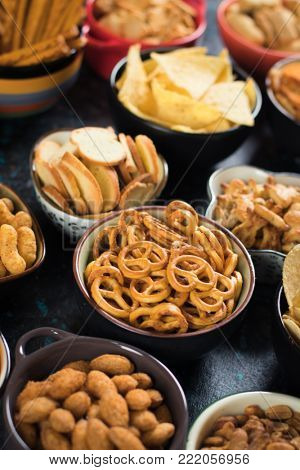 Salty snack including peanuts, potato chips and pretzels served as party food in bowls