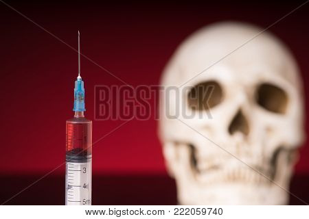 Blurry Skull and syringe, isolated on black red background