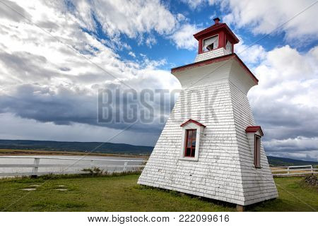 Anderson Hollow lighthouse by the Shepody River dam in Harvey, Bay of Fundy, New Brunswick. Summer day with rolling clouds. 