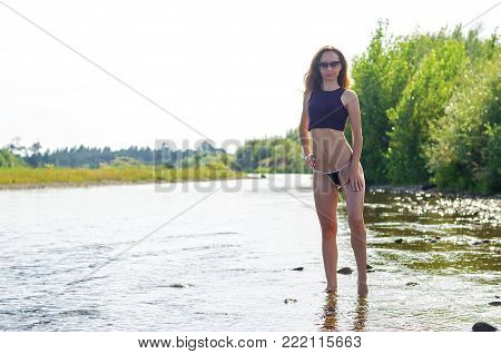 Beautiful young woman in a sexy lingerie on the river. Sexy woman posing in a mountain river.