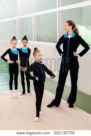 Gymnastics coach teaching little girls  in sporto gym