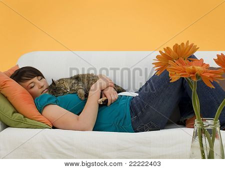 junge Frau mit eine kleine Katze auf einem Sofa schläft