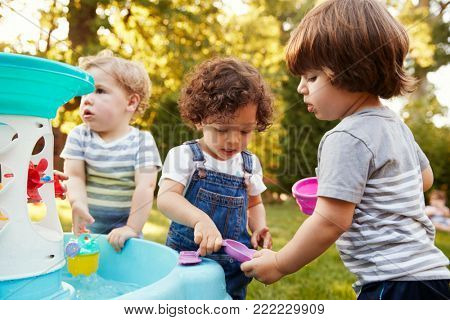 Group Of Young Children Playing With Water Table In Garden