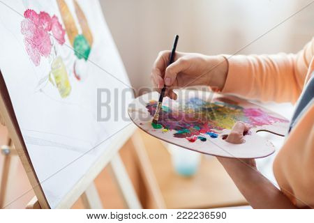 art, creativity and people concept - close up of artist with palette and brush painting still life on paper at studio