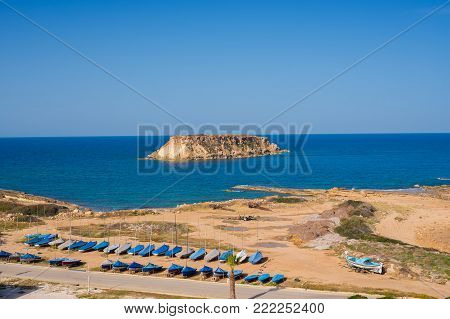 Shrouded boats on the seashore on a sunny day - a anticipation of adventure. Cyprus, the Akamas Peninsula.