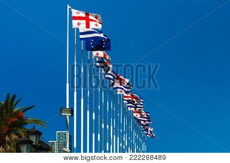 Large waving flag autonomous republic of Adjara and flag of Georgia, also known as the Five Cross Flag against the blue sky, Batumi, Adjara, Georgia