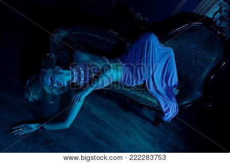 Gorgeous young superstar disturbed by paparazzi in the night club, lounge bar. Sitting on the couch. Hipster style. Indoor shot