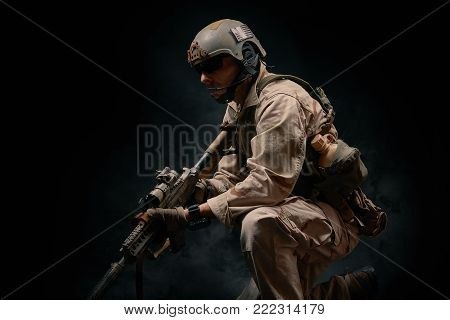 special forces soldier of the united states poses with a rifle on a black background