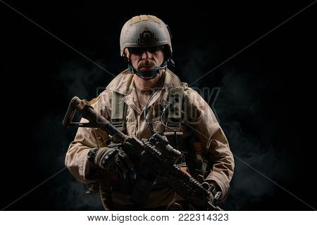 special forces soldier of the united states poses with a rifle on a black background