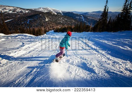 Snowboarder with snowboard rides through snow in forest tramplin. Freeride snowboarding in Sheregesh Ski Resort