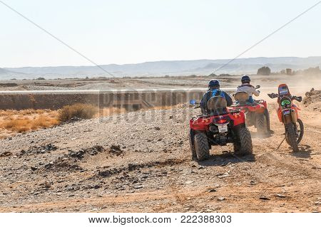 Merzouga, Morocco - February 25, 2016: Two Riders On Quad Atvs Wait Beside A Riderless Motorbike On 