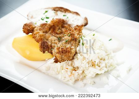 Traditional viennese Schnitzel with potato salad and rice on a withe plate