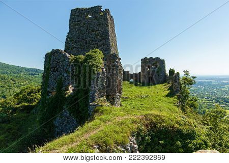 An abandoned fortress in the mountains, overgrown with grass against the background of mountains and sky, Georgia. Abandoned fortress in the mountains.