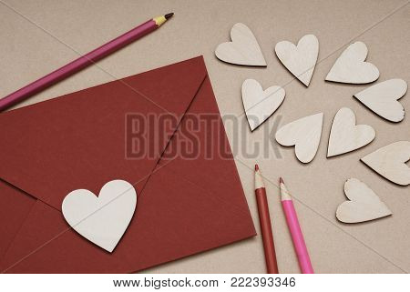 A heart shaped Valentine's Day card in a red envelope, surrounded by wooden