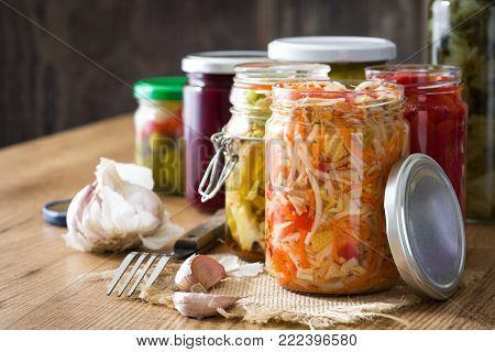 Fermented preserved vegetables in jar on wooden table. Copyspace