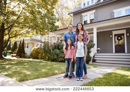 Portrait Of Smiling Family Standing In Front Of Their Home