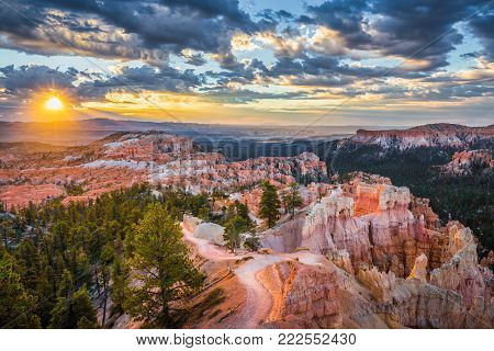 Classic view of Bryce Canyon National Park in beautiful golden morning light at sunrise with blue sky and dramatic clouds as seen from famous Sunrise Point in summer, Utah, American Southwest, USA