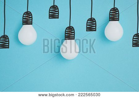 close up view of white lamps pretending hanging on lamp holders isolated on blue