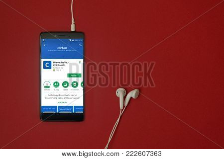 Los Angeles, January 11, 2018: Smartphone with Coinbase - bitcoin wallet application in google play store on red background with earphones plugged in and copy space