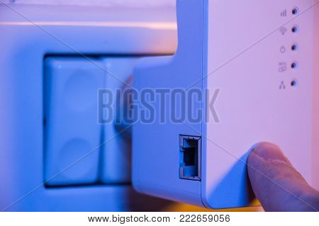 Man Press With His Finger On Wps Button On Wifi Repeater Which Is In Electrical Socket On The Wall