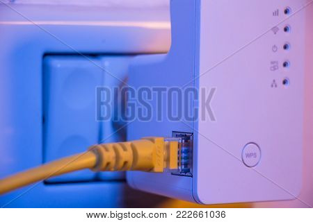 Wifi Extender In Electrical Socket On The Wall With Ethernet Cable Plugged In