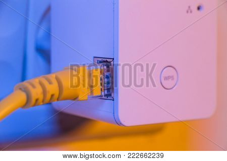 Wifi Extender In Electrical Socket On The Wall With Ethernet Cable Plugged In