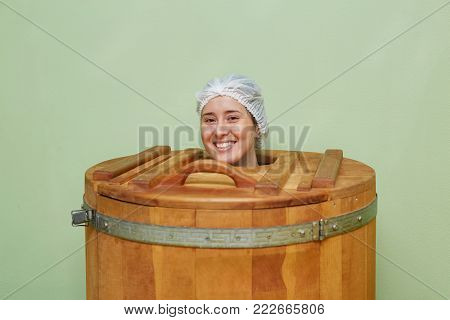 Beautiful girl in spa center. Wooden phyto cedar barrel sauna