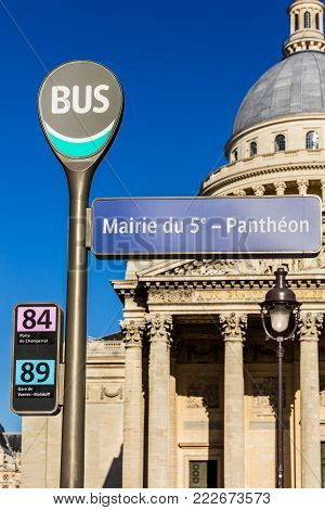 Paris, France - July 03, 2017: Pantheon bus stop sign with the Pantheon in the background in the summer at sunset.The Pantheon is a secular mausoleum containing the remains of distinguished French citizens.