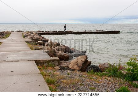 Woman walking on the pier in overcast weather
