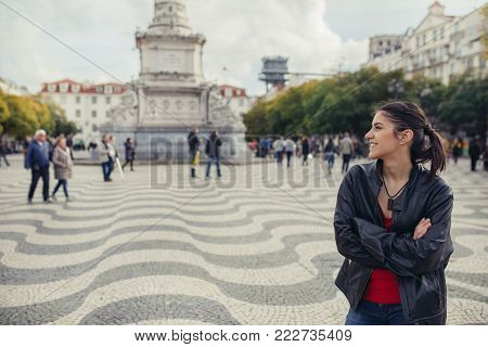 Enjoying beautiful warm and sunny day in Lisbon, Portugal.Sunset sun rays in small narrow street of colorful Lisbon.Experiencing charming european city.Smiling woman admiring Lisbon architecture