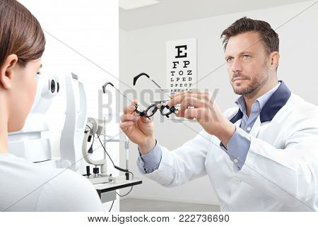 optometrist with trial frame examining eyesight  woman patient in optician office