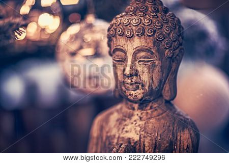 Vintage style photo of the wooden statue of Buddha, God of oriental religion, conceptual picture of meditation, mindfulness and inner peace