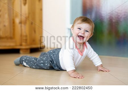 Little cute baby girl learning to crawl. Healthy child crawling in kids room. Smiing happy girl. Cute toddler discovering home and learning different skills.