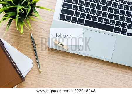 Workplace Top View Of  Wooden Desktop With Laptop, Pen, Notebook And Paper Note For Holiday Summer C