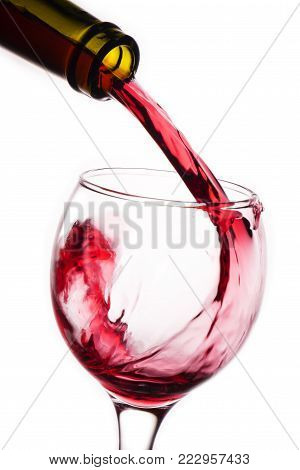 Closeup of red wine pouring into glass on white