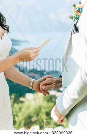 The Bride Reads Her Oath To The Groom And They Hold Hands.
